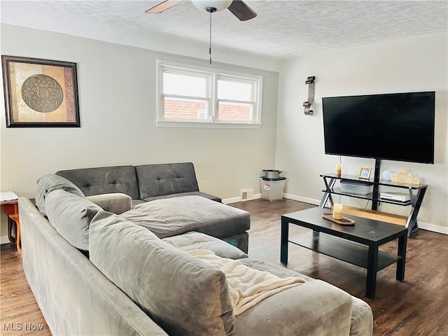 living room featuring ceiling fan, hardwood / wood-style flooring, and a textured ceiling