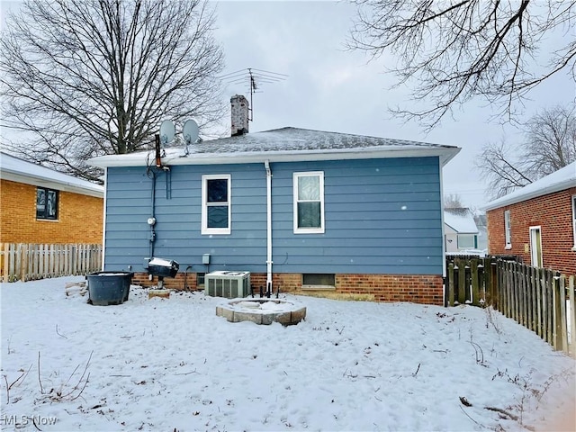 snow covered rear of property featuring central air condition unit