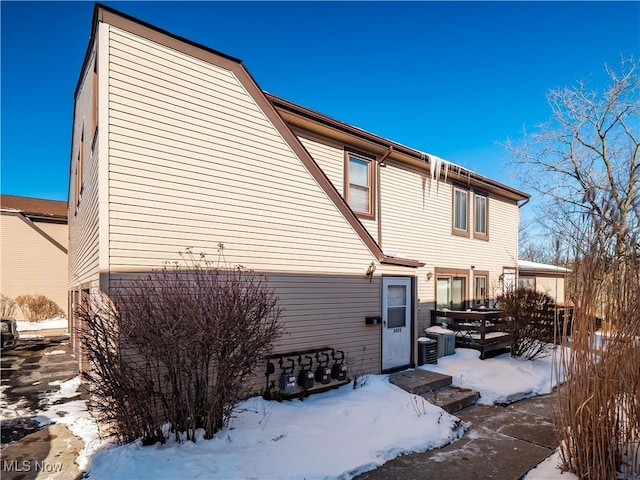 snow covered rear of property with central air condition unit