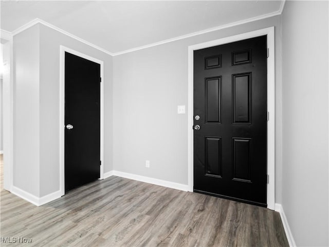 entryway with ornamental molding and light hardwood / wood-style floors