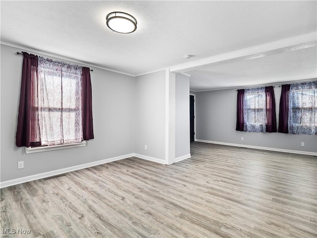 spare room featuring crown molding, a textured ceiling, and light wood-type flooring