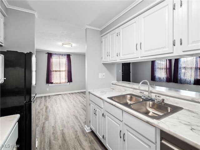 kitchen featuring black refrigerator, sink, and white cabinets