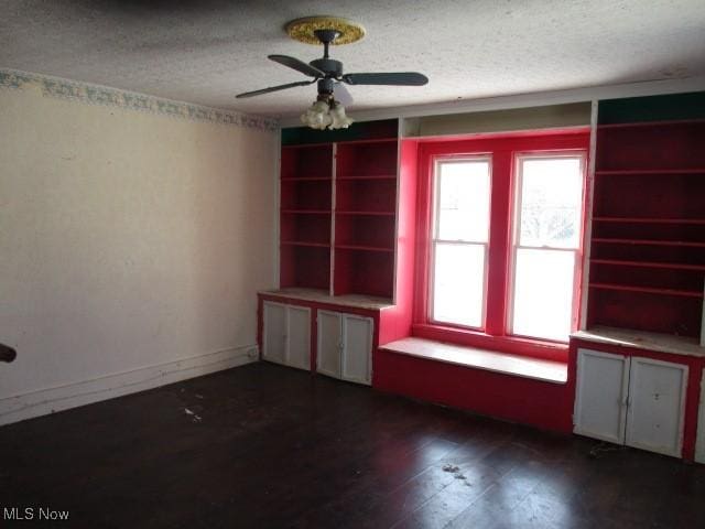 unfurnished room with ceiling fan, dark wood-type flooring, and a textured ceiling