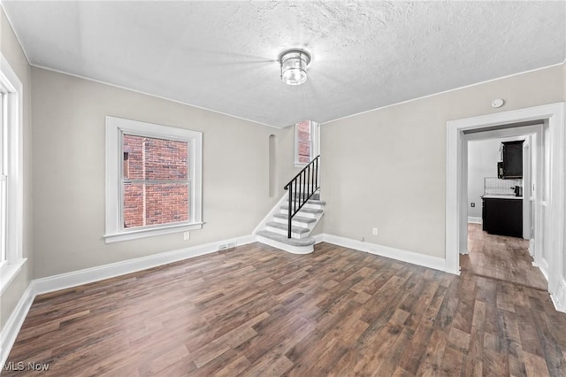 unfurnished living room with dark hardwood / wood-style floors and a textured ceiling