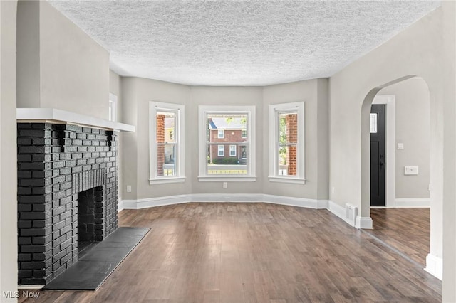 unfurnished living room featuring a fireplace, wood-type flooring, and a textured ceiling