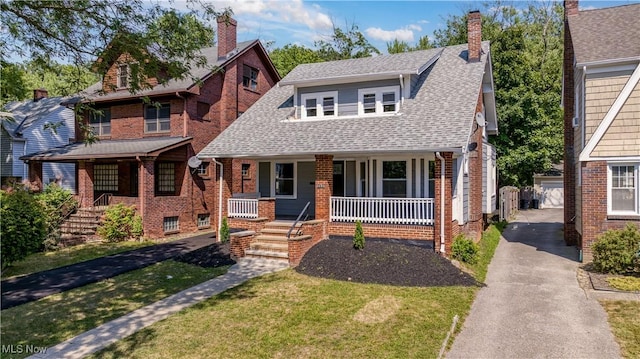 tudor house with a garage, an outdoor structure, a front yard, and covered porch