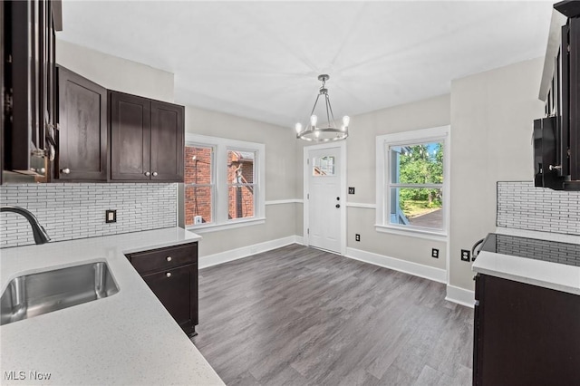 kitchen with sink, tasteful backsplash, dark brown cabinetry, dark hardwood / wood-style flooring, and decorative light fixtures