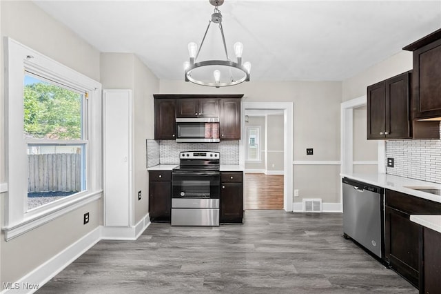 kitchen with dark brown cabinetry, a chandelier, pendant lighting, stainless steel appliances, and hardwood / wood-style floors