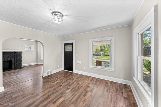 unfurnished living room featuring dark wood-type flooring, a textured ceiling, and a fireplace