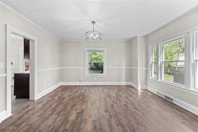 unfurnished room featuring dark wood-type flooring, crown molding, and an inviting chandelier