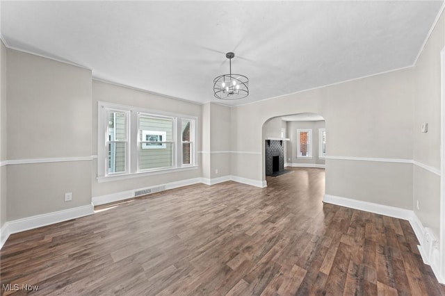 unfurnished living room with a fireplace, plenty of natural light, dark hardwood / wood-style floors, and a notable chandelier