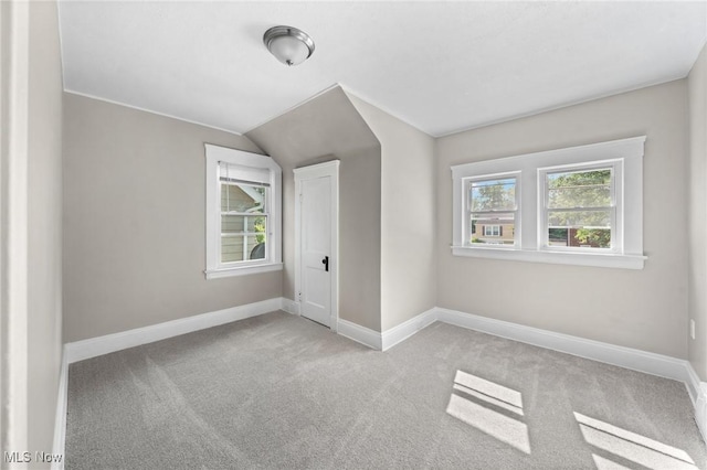 additional living space featuring light colored carpet and lofted ceiling