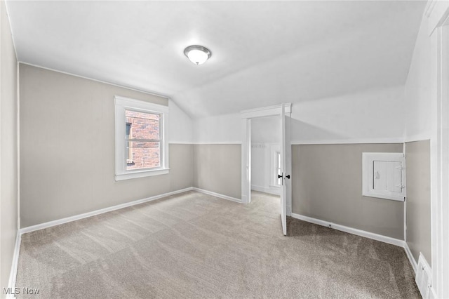 additional living space featuring light colored carpet and vaulted ceiling