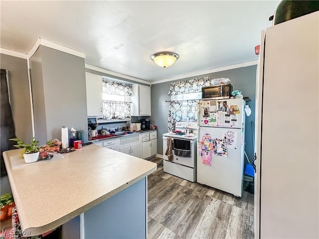 kitchen with a breakfast bar area, white cabinets, kitchen peninsula, white appliances, and light hardwood / wood-style flooring