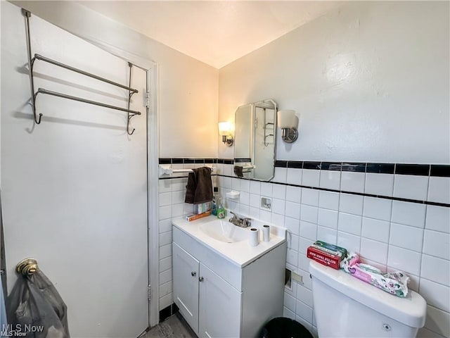 bathroom with vanity, tile walls, and toilet