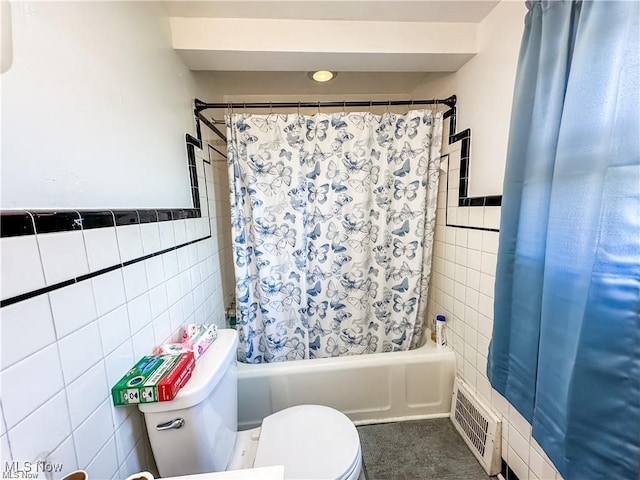 bathroom featuring toilet, shower / tub combo, and tile walls