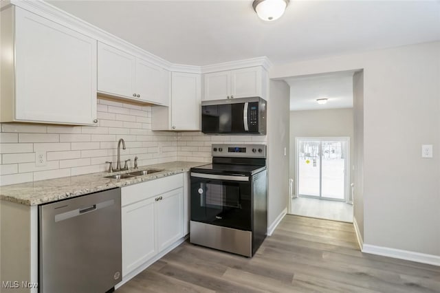 kitchen with light stone countertops, appliances with stainless steel finishes, sink, and white cabinets