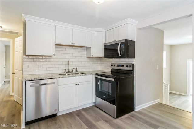 kitchen with white cabinetry, stainless steel appliances, light stone countertops, and light hardwood / wood-style floors