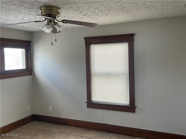 carpeted empty room with ceiling fan and a textured ceiling