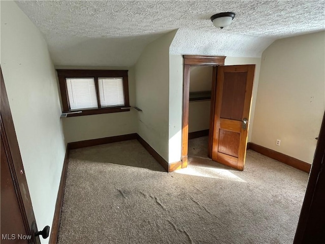 carpeted empty room with lofted ceiling and a textured ceiling