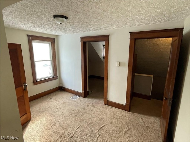 carpeted empty room featuring a textured ceiling