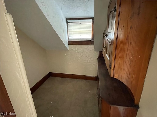 interior space with a textured ceiling and dark colored carpet