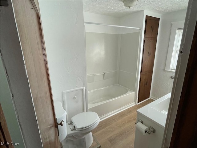 full bathroom with toilet, a textured ceiling, vanity, hardwood / wood-style flooring, and shower / bath combination