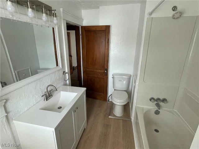 full bathroom with bathtub / shower combination, toilet, a textured ceiling, vanity, and hardwood / wood-style flooring