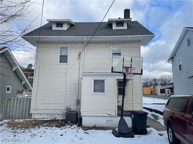 snow covered rear of property featuring central AC