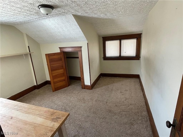 unfurnished bedroom with vaulted ceiling, a textured ceiling, and carpet