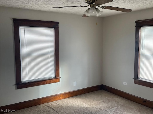 unfurnished room with ceiling fan, plenty of natural light, a textured ceiling, and carpet