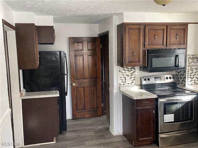 kitchen with dark brown cabinetry, black appliances, a textured ceiling, dark hardwood / wood-style flooring, and decorative backsplash