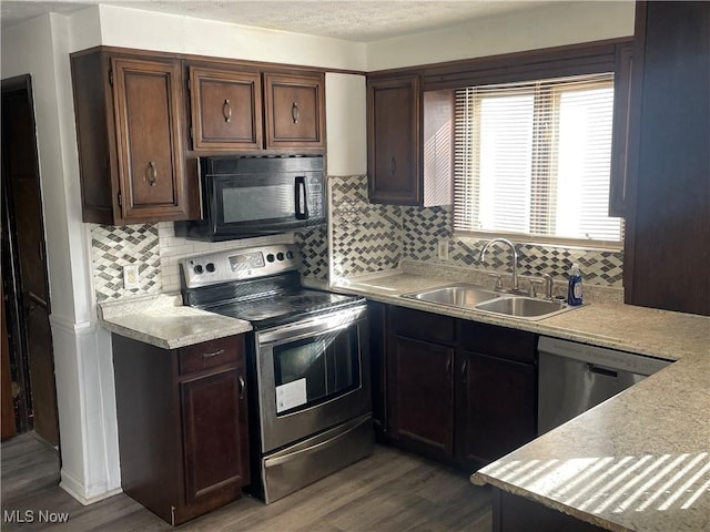 kitchen featuring wood-type flooring, appliances with stainless steel finishes, sink, and backsplash