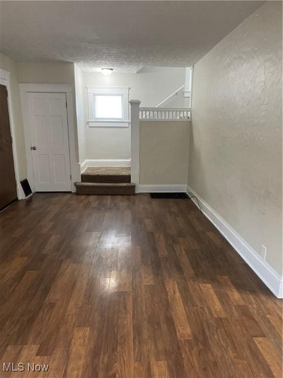 spare room featuring dark wood-type flooring and a textured ceiling