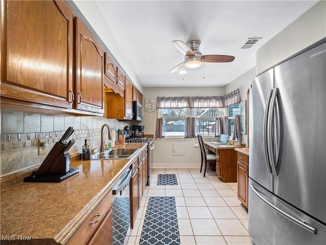 kitchen with sink, light tile patterned floors, appliances with stainless steel finishes, ceiling fan, and backsplash