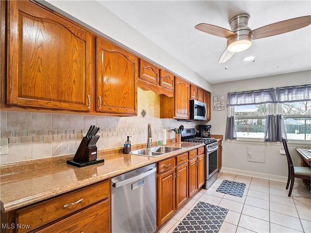 kitchen with tasteful backsplash, sink, light tile patterned floors, light stone counters, and stainless steel appliances