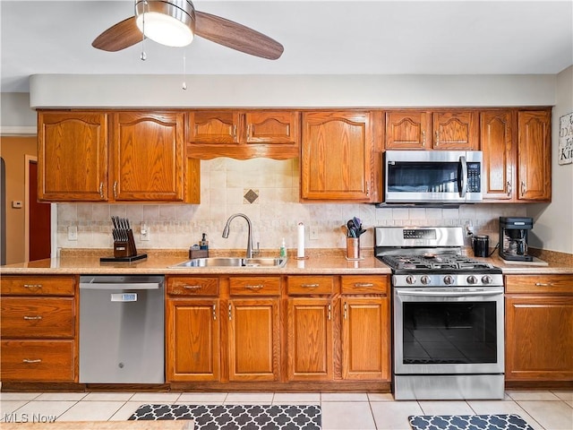 kitchen featuring sink, light tile patterned floors, ceiling fan, appliances with stainless steel finishes, and decorative backsplash