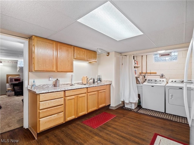 laundry area featuring separate washer and dryer, sink, and dark hardwood / wood-style flooring