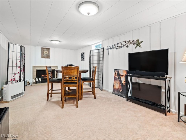 dining area with a brick fireplace and light colored carpet