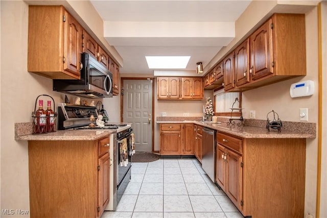 kitchen with light tile patterned floors, a skylight, and stainless steel appliances