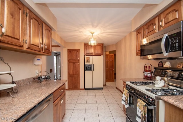 kitchen with hanging light fixtures, light stone countertops, appliances with stainless steel finishes, and light tile patterned flooring