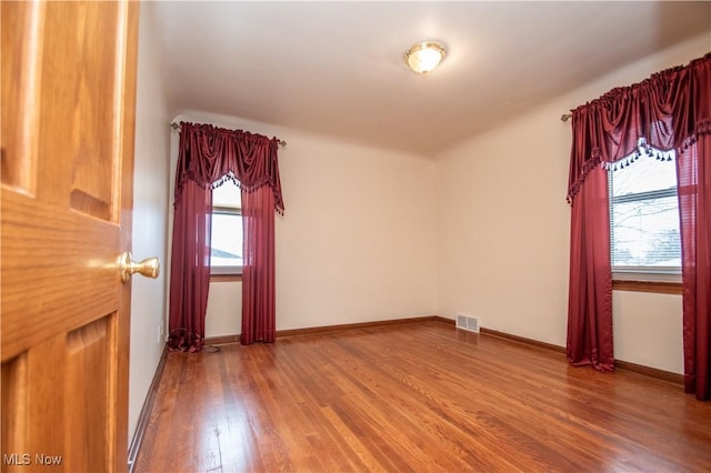 spare room featuring plenty of natural light and hardwood / wood-style floors