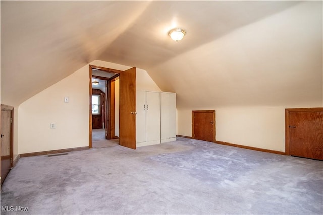 bonus room with vaulted ceiling and light colored carpet