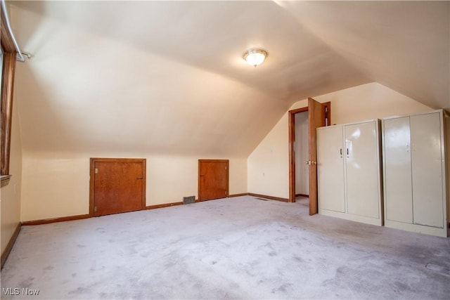 additional living space featuring light colored carpet and lofted ceiling