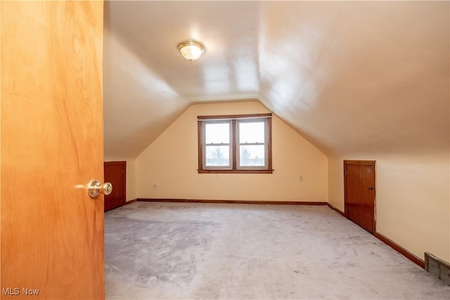 bonus room with vaulted ceiling and light carpet