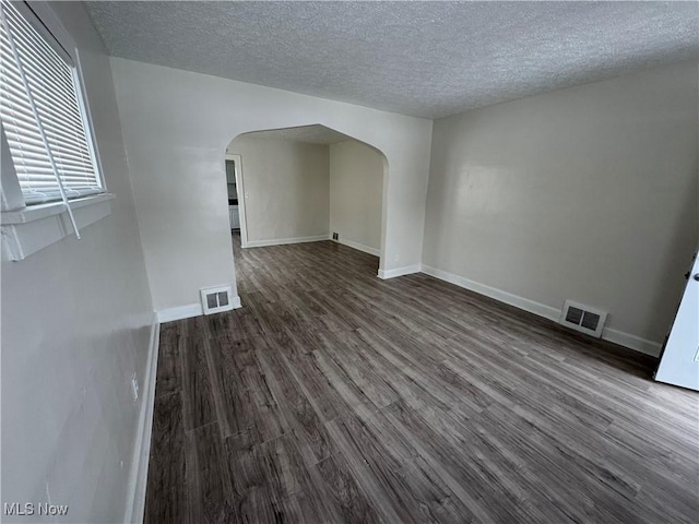 unfurnished living room featuring dark wood-type flooring and a textured ceiling