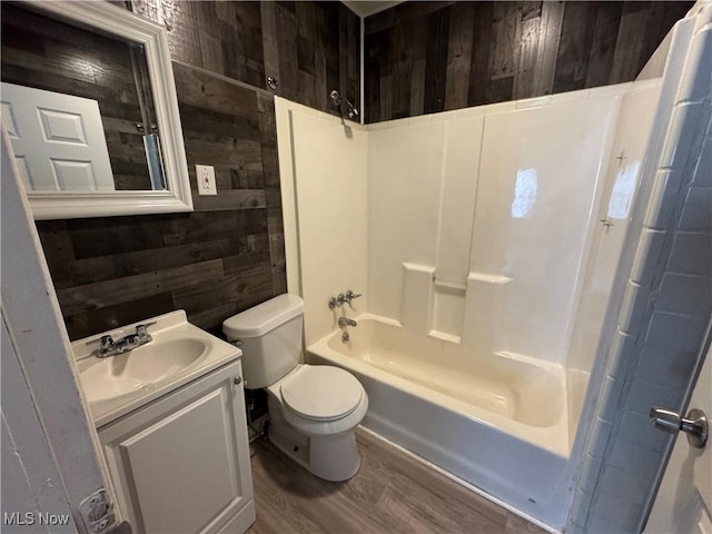 full bathroom with toilet, wood walls, shower / bathtub combination, vanity, and hardwood / wood-style floors