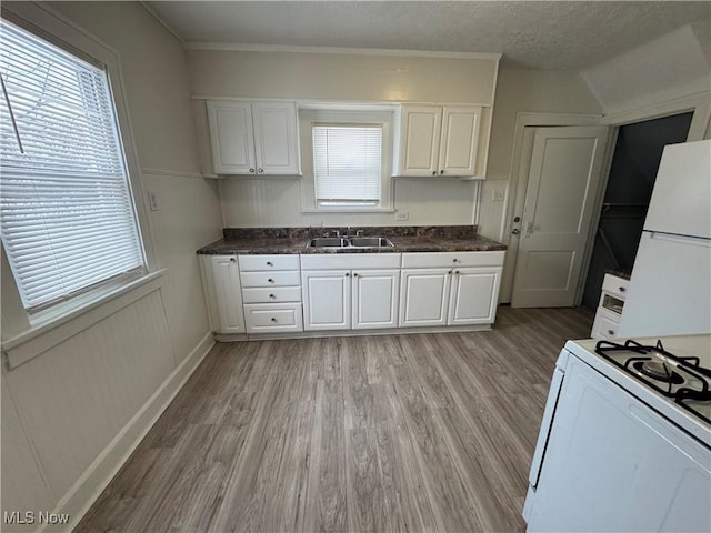 kitchen featuring sink, white appliances, light hardwood / wood-style flooring, white cabinetry, and a textured ceiling