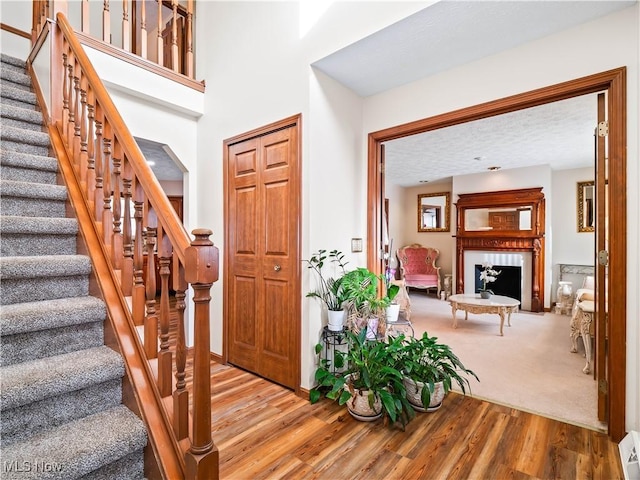 foyer entrance with a fireplace, wood finished floors, stairs, and carpet