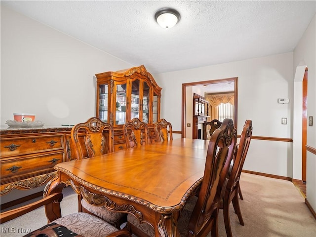 dining room with light carpet and a textured ceiling